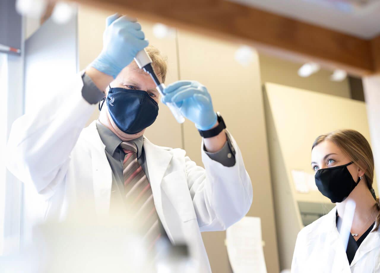 Professor Christian Eggers performs a lab experiment as a student watches